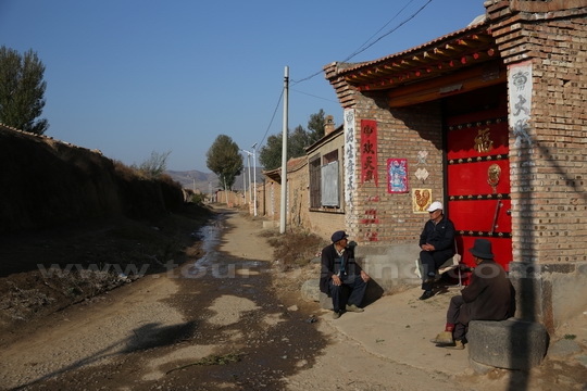 Senior villagers are seen chatting and sunshine bathing.