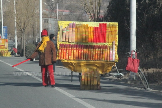 Several incense vendors are standing by the main road selling incense sticks for people to burn inside