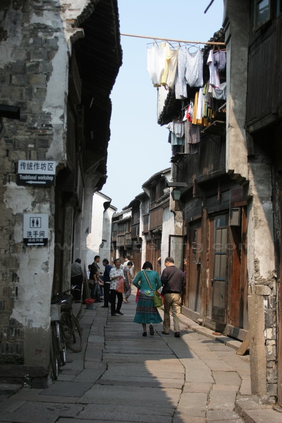 Stroll on the narrow lane paved with stone slabs with the hanging laundry that sways overhead