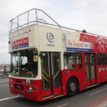 The Orignal Bus is passing a bridge over the Thames River
