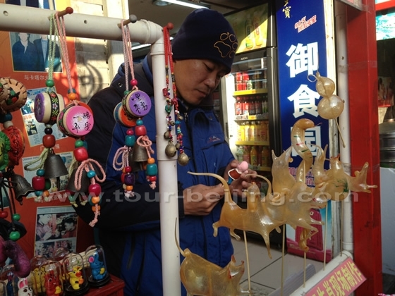 The craftman is blowing sugar figurines on the spot.