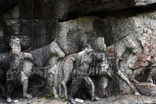 The relief scripture features three striding human figures leading two horses 