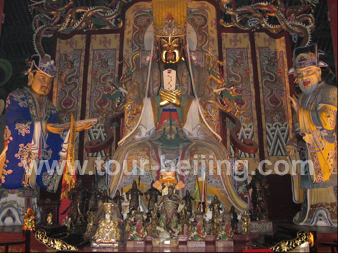 The statue in the middle is the apotheosized Guan Yu, dressed up like an emperor. There are two many small statues on his foot with different posture, different postures indicating different means.