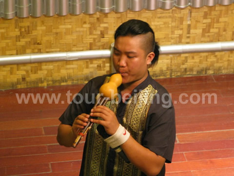 A Dai boy is playing a minority musical instrument