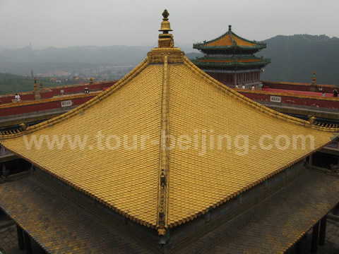 The golden roof of the temple atop the red terrace