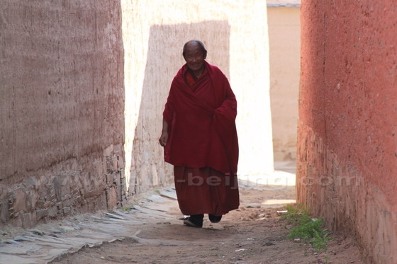 Here comes a smiling monk walking from his living quarters