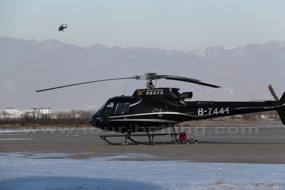 One helicopter is flying and the other is waiting for the instruction.