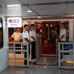The boat staff persons are standing at the boarding gate welcoming us
