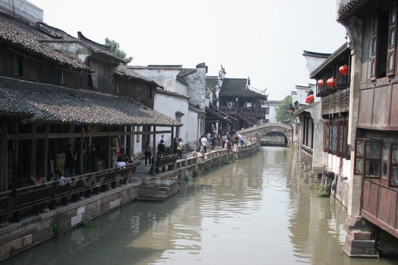 The narrow street with long chairs goes along the canal