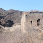 taking a picture of the tower sitting on an overgrown and crumbling wall winding up on the hillside