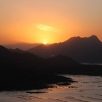 the rising sun half over the mountain line in the distance
