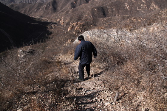 Walk along a makeshift dirt path below the wall