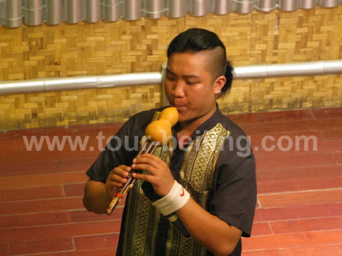 A Dai boy is playing a minority musical instrument